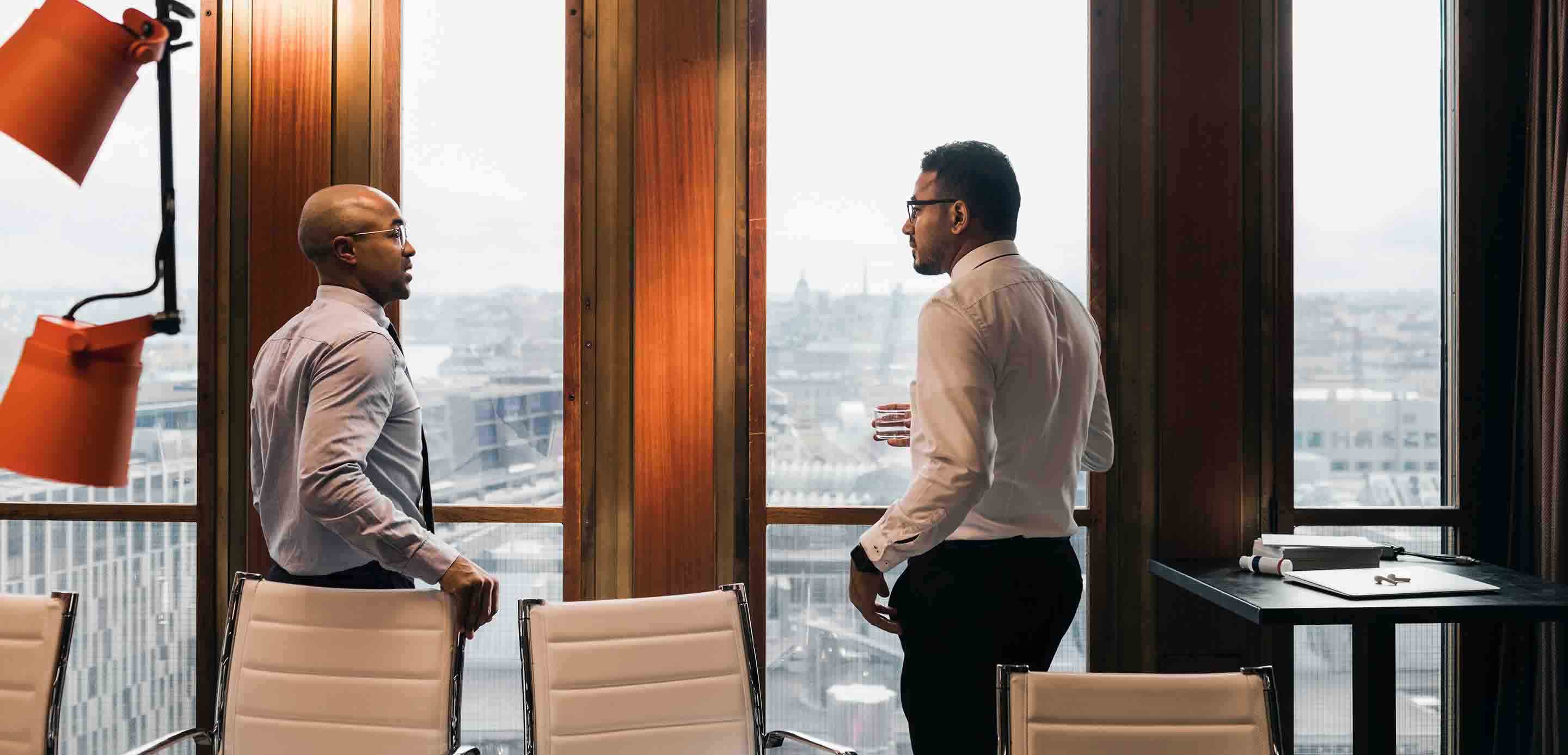 Two people in a corporate environment standing in front of a window
