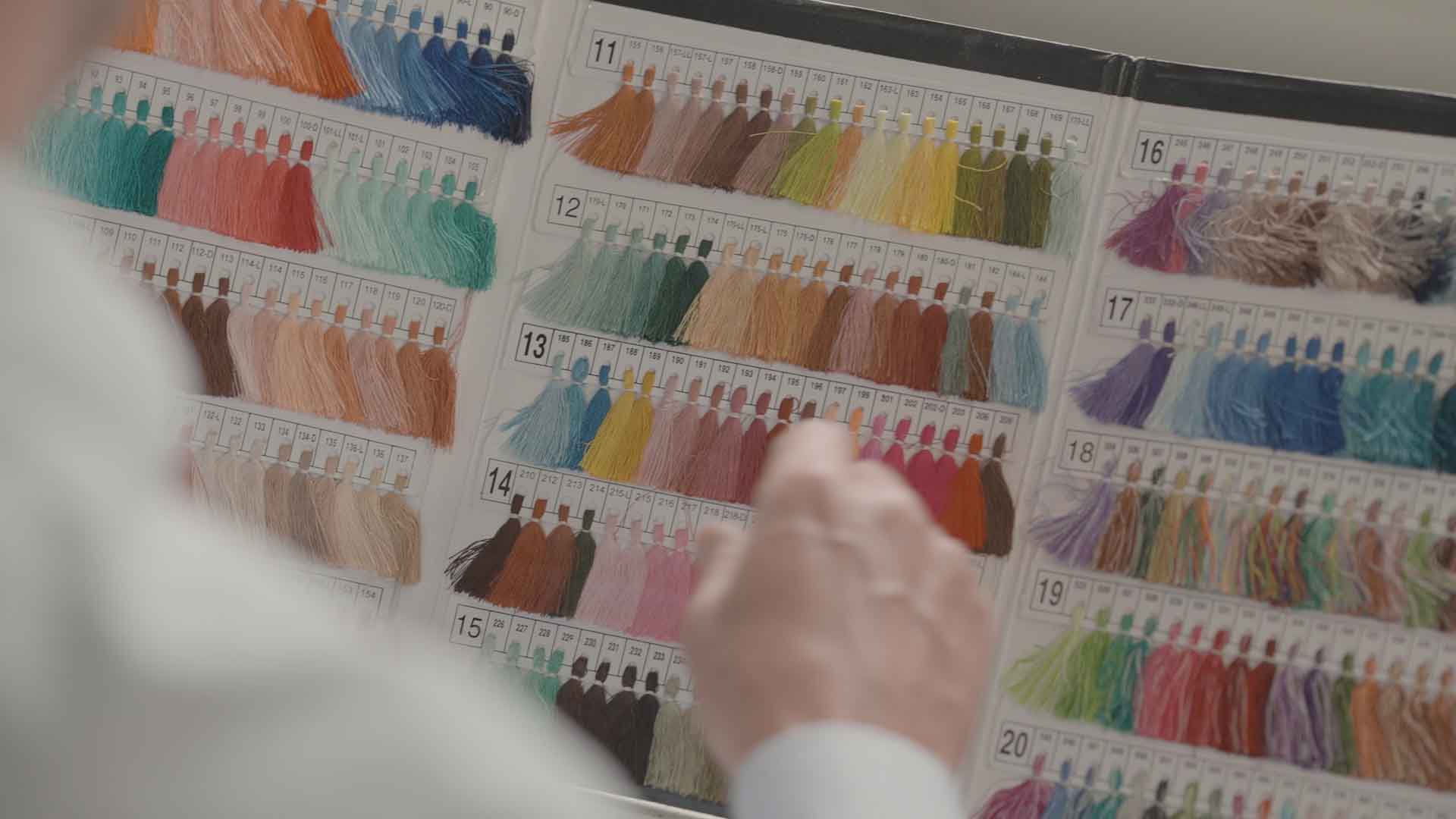 A close up of a person pointing at lots of different coloured tassels