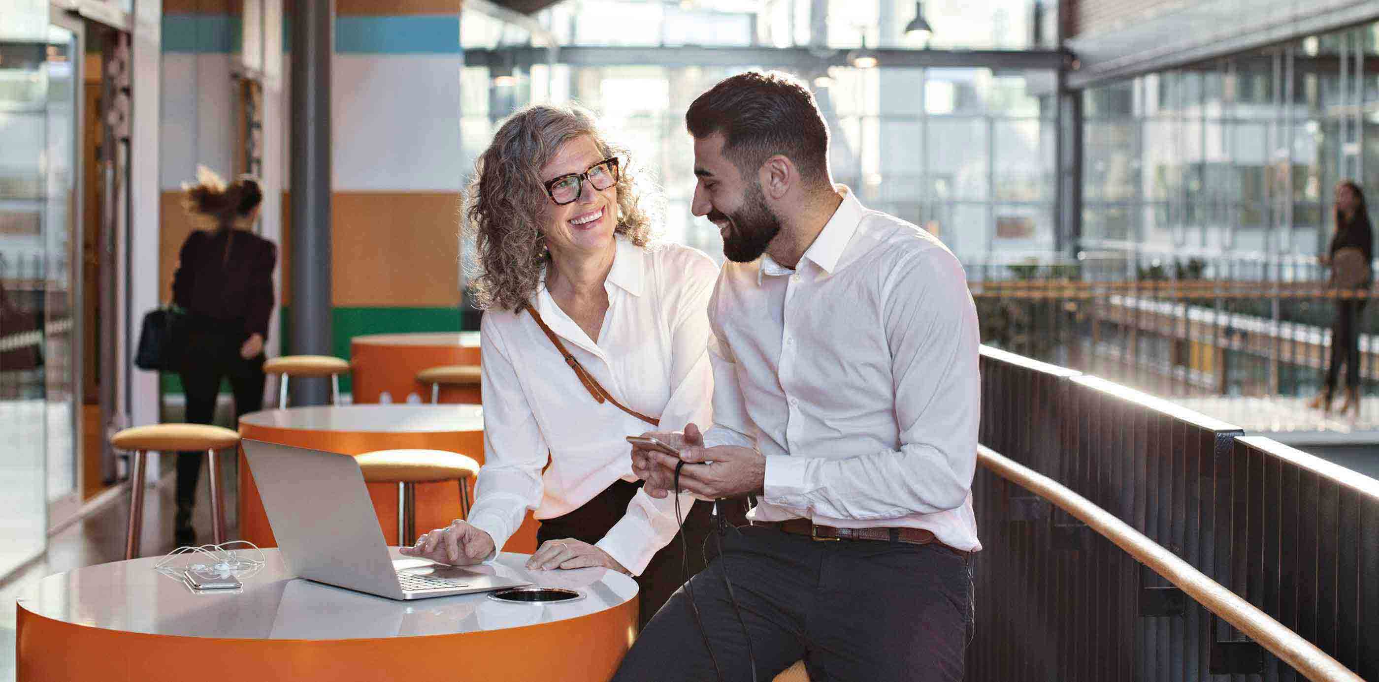 Man and woman in a meeting on a terrace with a laptop smiling