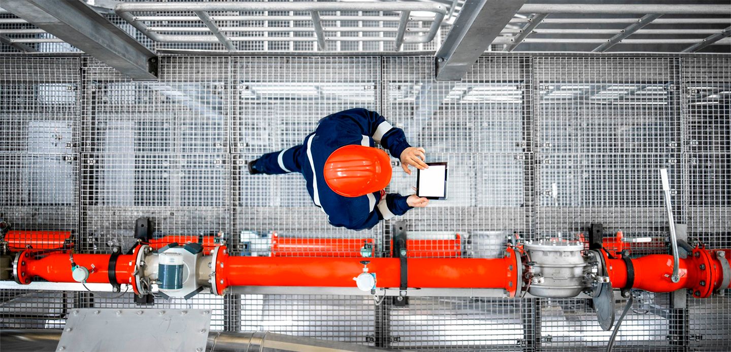 Worker in hard hat reviewing pipes and checking screen