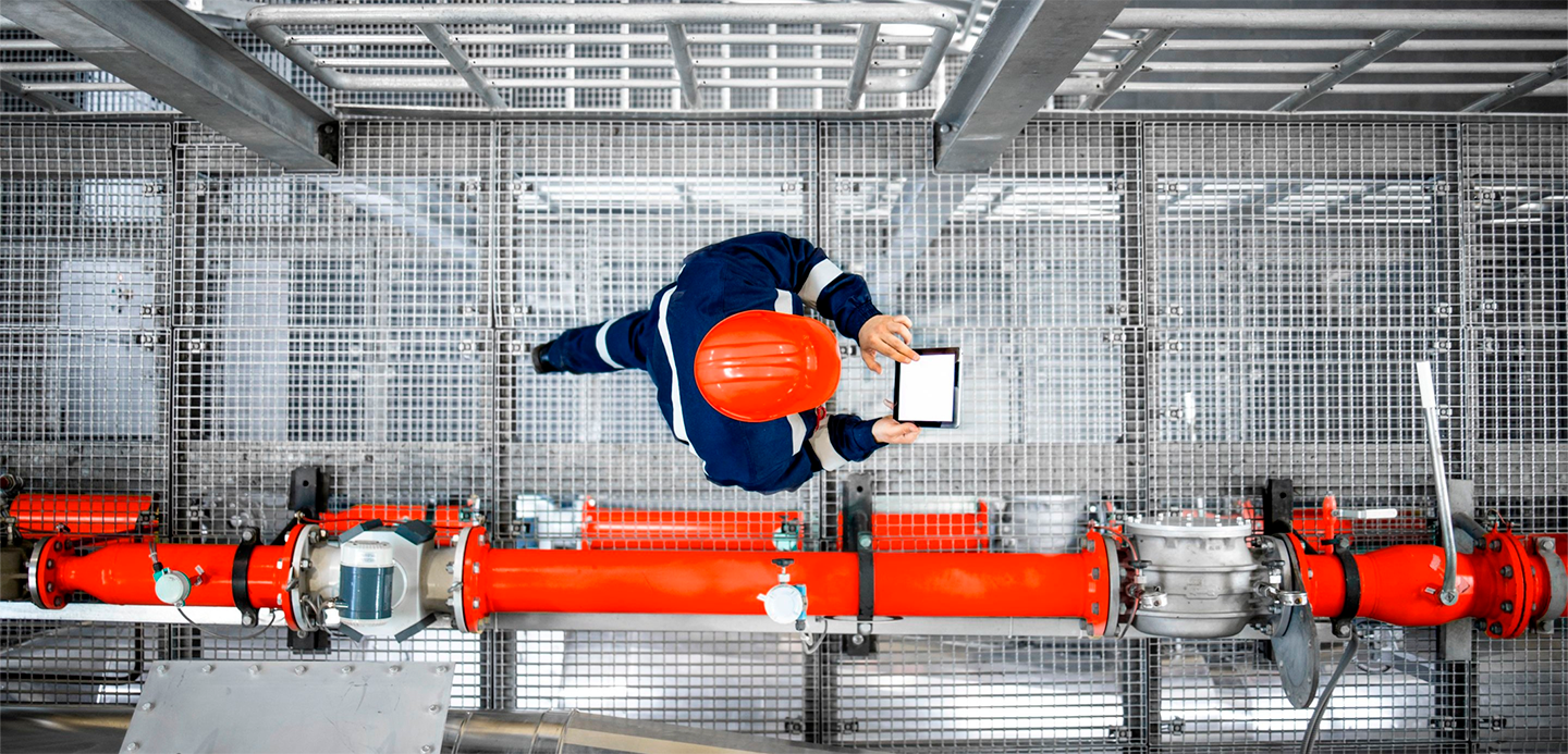 Worker in hard hat reviewing pipes and checking screen