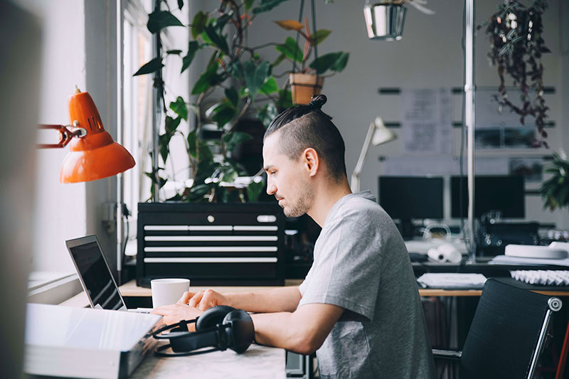 Person sitting at a desk in an office working on laptop Person sitting at a desk in an office working on laptop