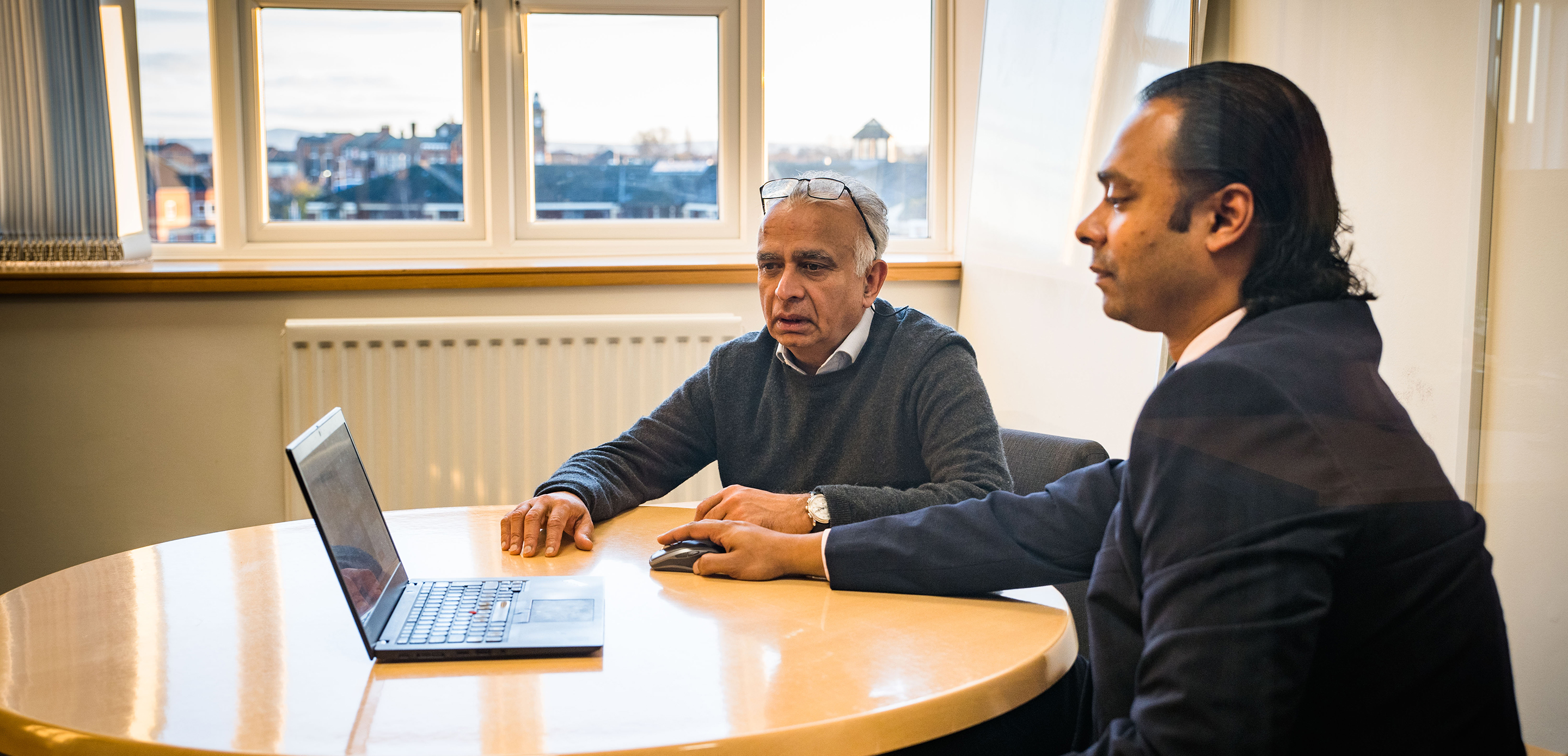 Two men looking at a laptop in a meeting room