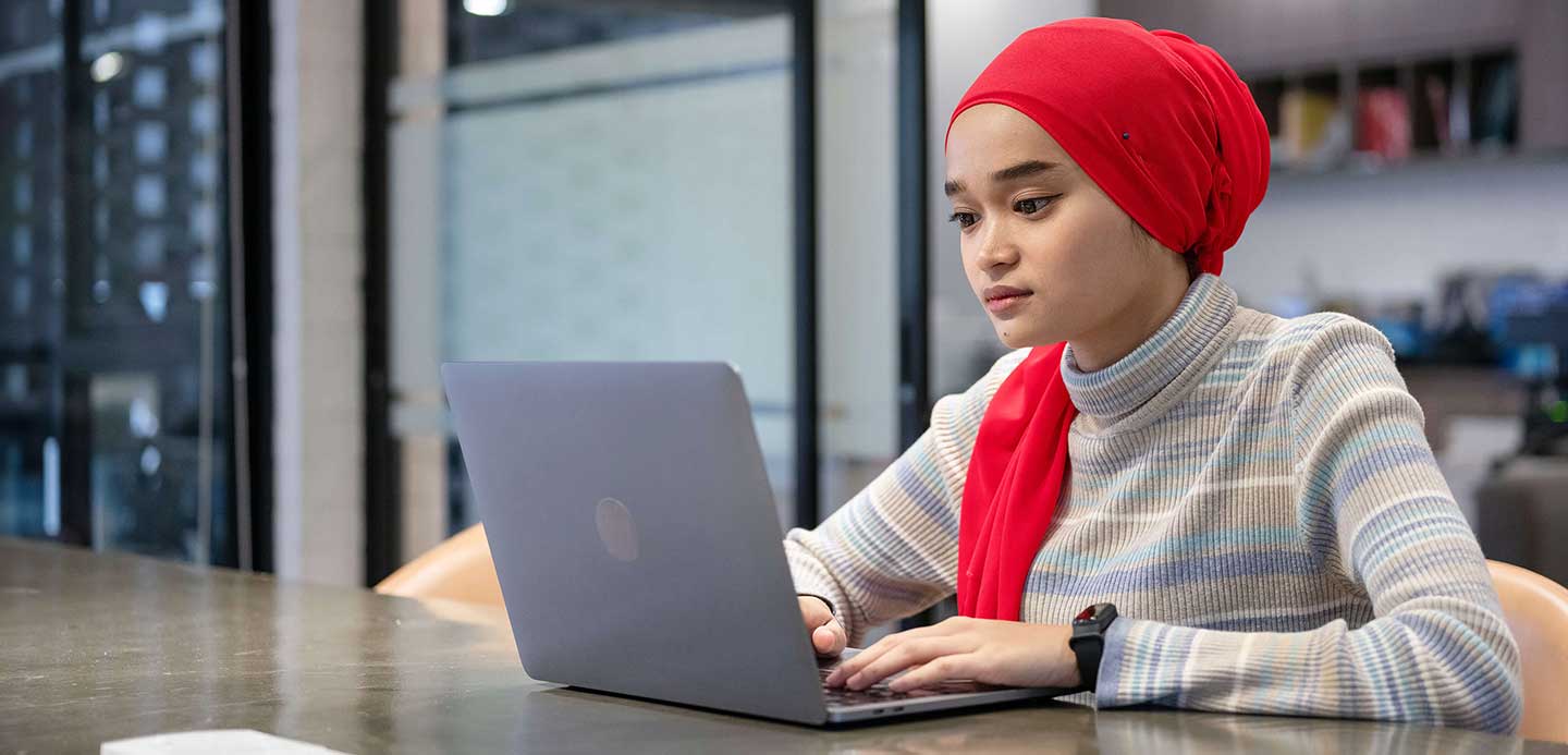 Woman sitting working on laptop in a corporate office space Woman sitting working on laptop in a corporate office space
