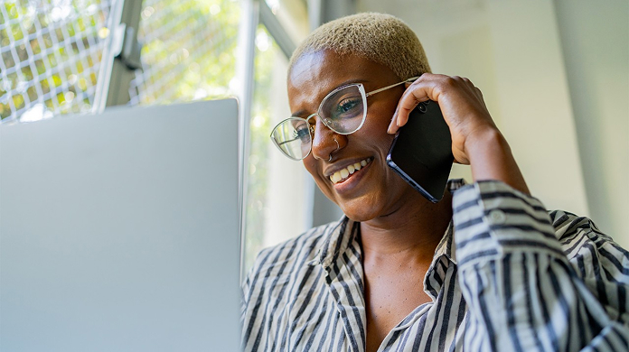 Person on mobile phone looking at laptop