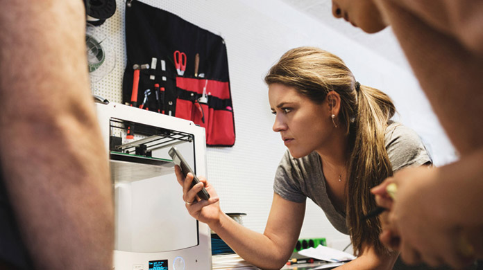 Woman holding mobile phone in workshop