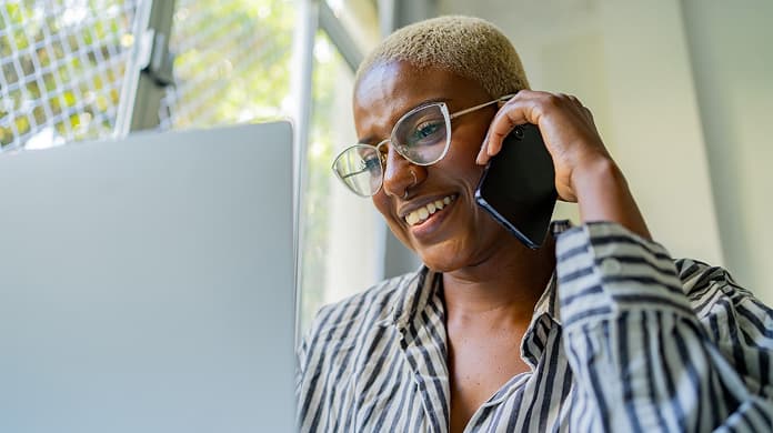 Person on mobile phone looking at laptop